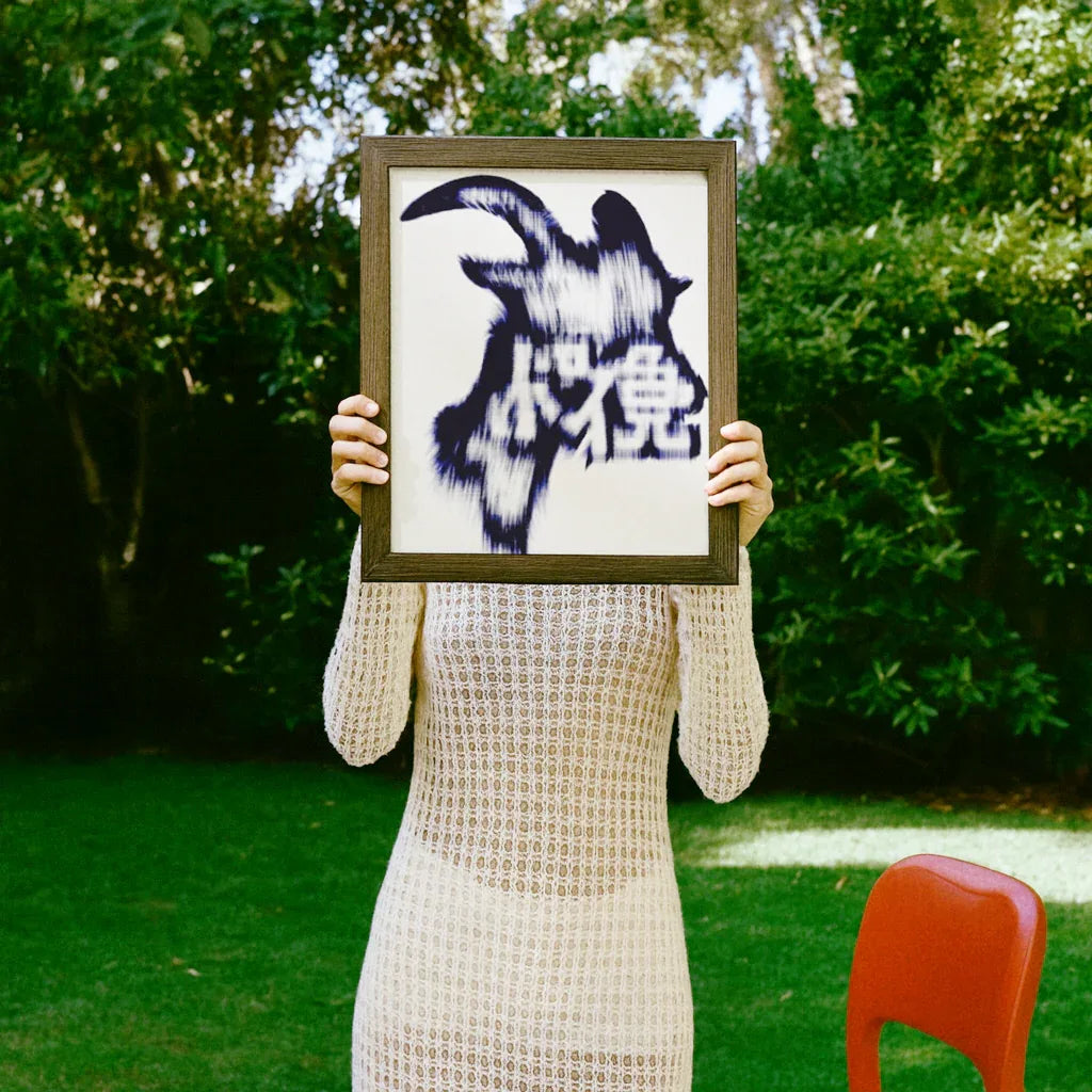 Bergziege Poster im Rahmen, gehalten von einer Person in einem weißen Oberteil im Freien