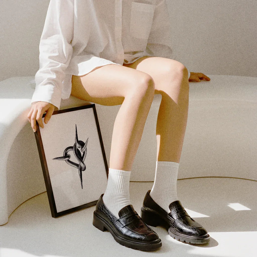 Das Herz Ketten Poster im Rahmen, gehalten von einer Person in einem weißen Hemd und schwarzen Schuhen