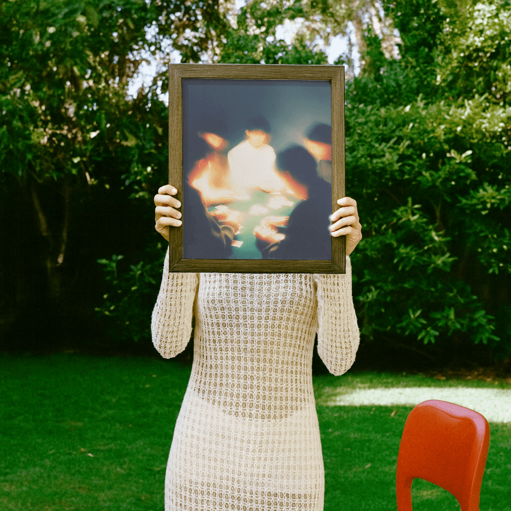 Karten spielen Poster in einem Rahmen, gehalten von einer Person im Freien vor grünem Hintergrund