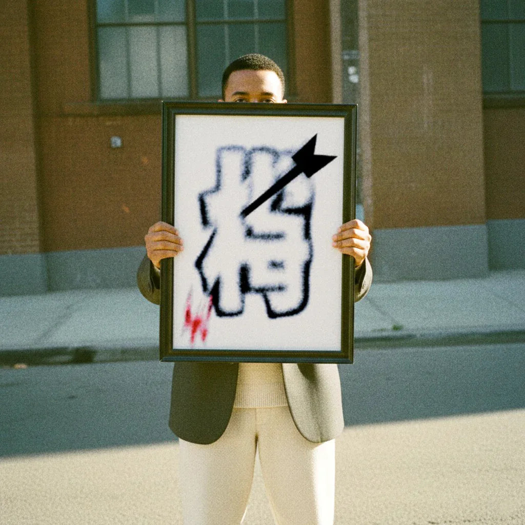 Mann hält ein modernes Poster abstrakt in einem schwarzen Rahmen vor einem urbanen Hintergrund