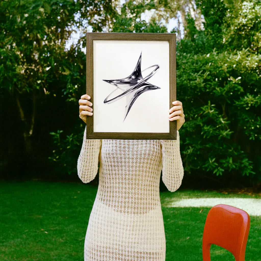 Moderne Poster Chrome Orbit in einem Rahmen, präsentiert von einer Person im Freien