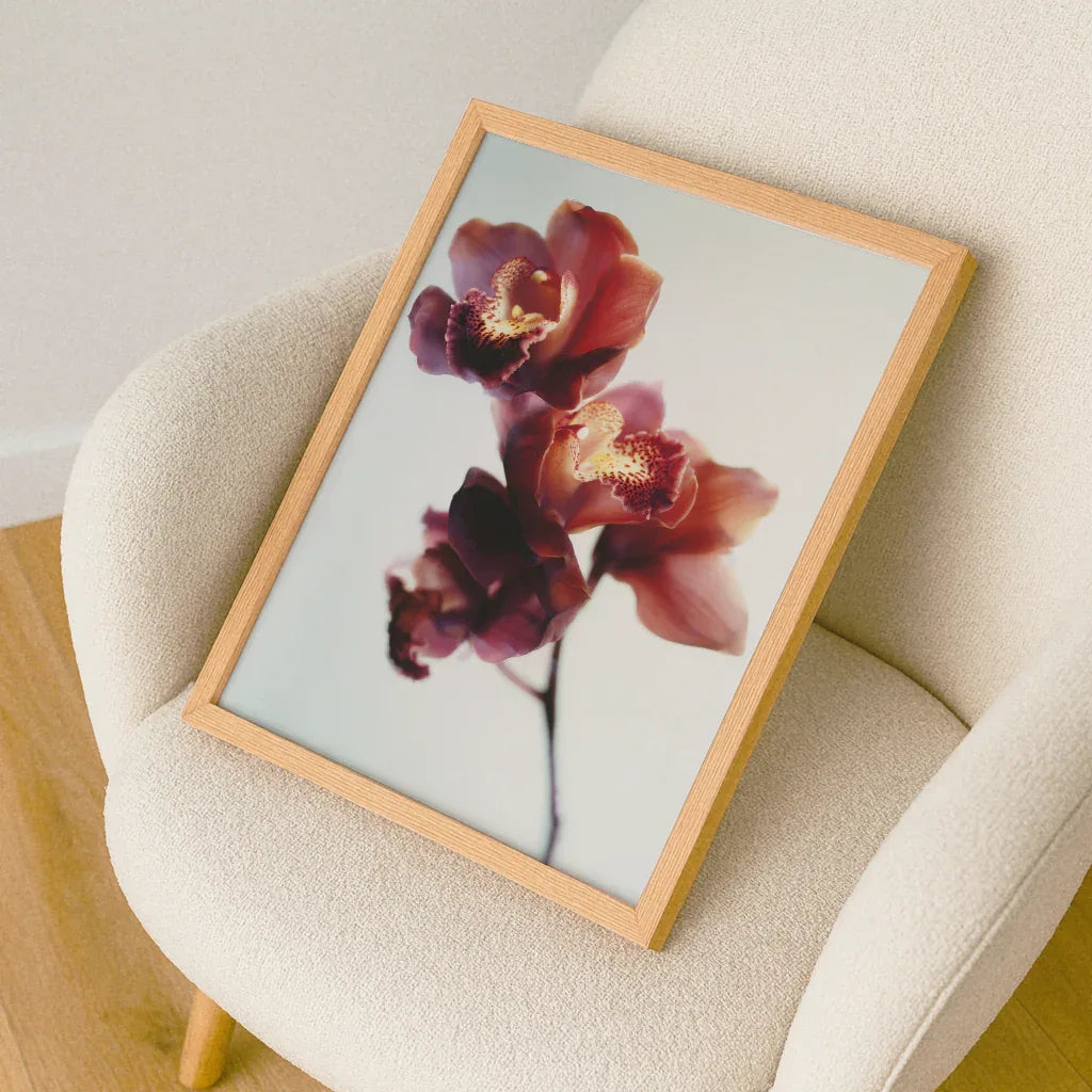 Elegantes Orchideen Poster mit sanften Farben in einem Holzrahmen auf einem modernen Stuhl